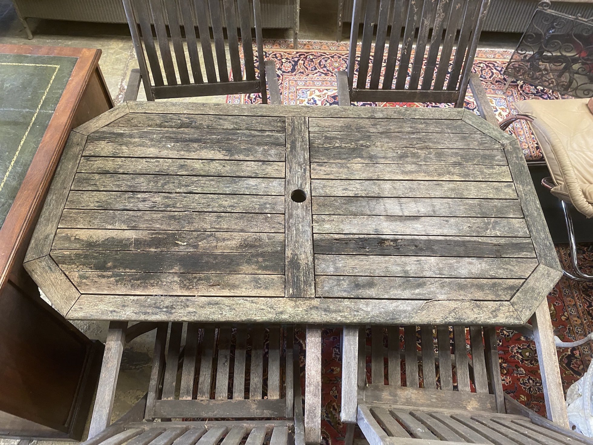 A weathered teak folding garden table, width 150cm, depth 80cm, height 70cm together with four folding teak elbow chairs